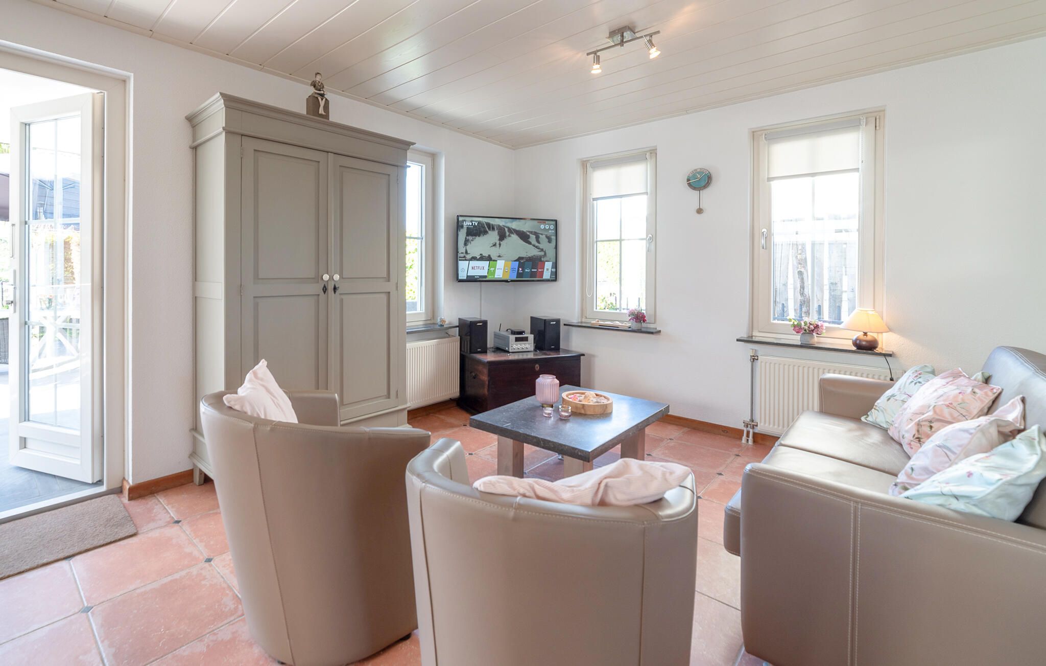 A living room with a sofa set, a coffee table, a television mounted on the wall, and a cabinet.