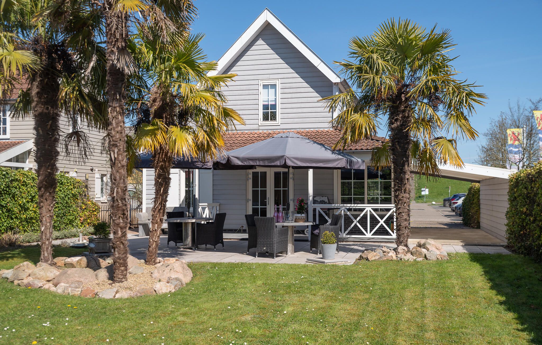 Una casa con patio que incluye mobiliario exterior y una zona de estar cubierta.