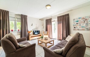 A living room with two sofas, a coffee table, a TV, and a wall with pictures. - 3 bedroom lovely home in Wemeldinge (Wemeldinge)