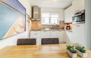 A modern kitchen with white cabinets, a stainless steel oven, and a large window. - 3 bedroom lovely home in Wemeldinge (Wemeldinge)