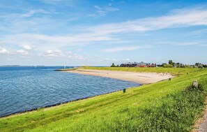A coastal landscape with a sandy beach, grassy areas, and a building with a red roof. - 3 bedroom lovely home in Wemeldinge (Wemeldinge)