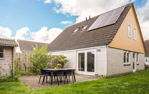A residential property with a brick exterior, a tiled roof, and a small patio area with a table and chairs. - 3 bedroom lovely home in Wemeldinge (Wemeldinge)
