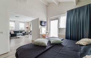 A bedroom with a bed, a desk, a chair, a television, and a window with curtains. - Gorgeous home in Wemeldinge with sauna (Wemeldinge)