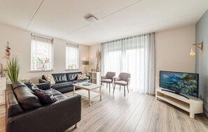 Ein modernes Wohnzimmer mit einer Ledersofa, zwei Sesseln, einem Couchtisch und einem Flachbildfernseher.