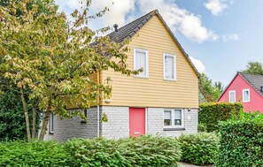 A two-story house with a red door, a small window on the ground floor, and a larger window on the upper floor. - Gorgeous home in Wemeldinge with sauna (Wemeldinge)