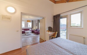 Ein Schlafzimmer mit einem Bett, einem Schreibtisch, einem Sessel, einer Couch und einem Fenster.