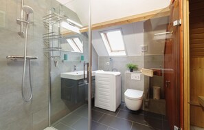 Ein modernes Badezimmer mit Duschkabine aus Glas, einem weißen Waschbecken und einer Toilette.