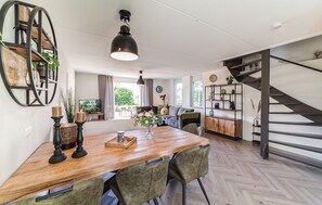 A modern kitchen with a wooden dining table, chairs, and a hanging light fixture. - Awesome home in Wemeldinge with sauna (Wemeldinge)