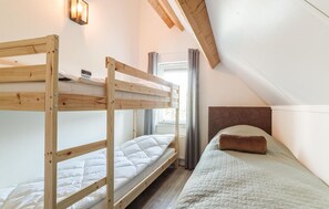 A dormitory room with bunk beds, a window with curtains, and a headboard. - Awesome home in Wemeldinge with sauna (Wemeldinge)