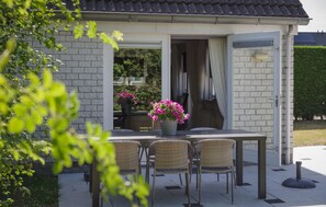An outdoor dining area with a table and chairs, a potted plant, and a building entrance. - Nice home in Wemeldinge with WiFi (Wemeldinge)
