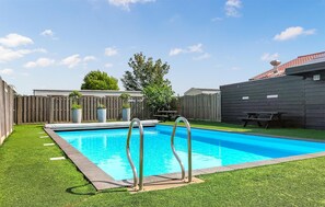 A backyard with a swimming pool, a wooden fence, and a picnic table.