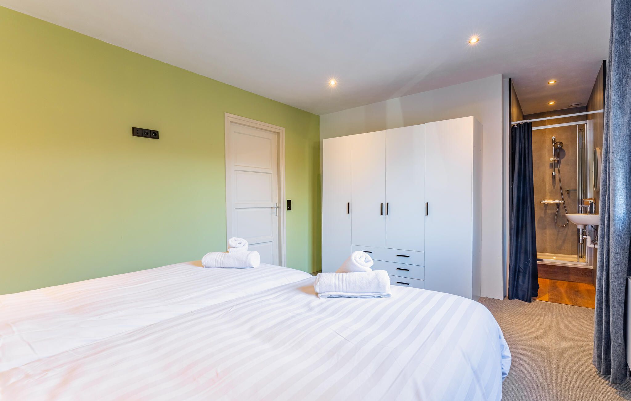 Una habitación de hotel con dos camas, un armario y un baño con ducha.