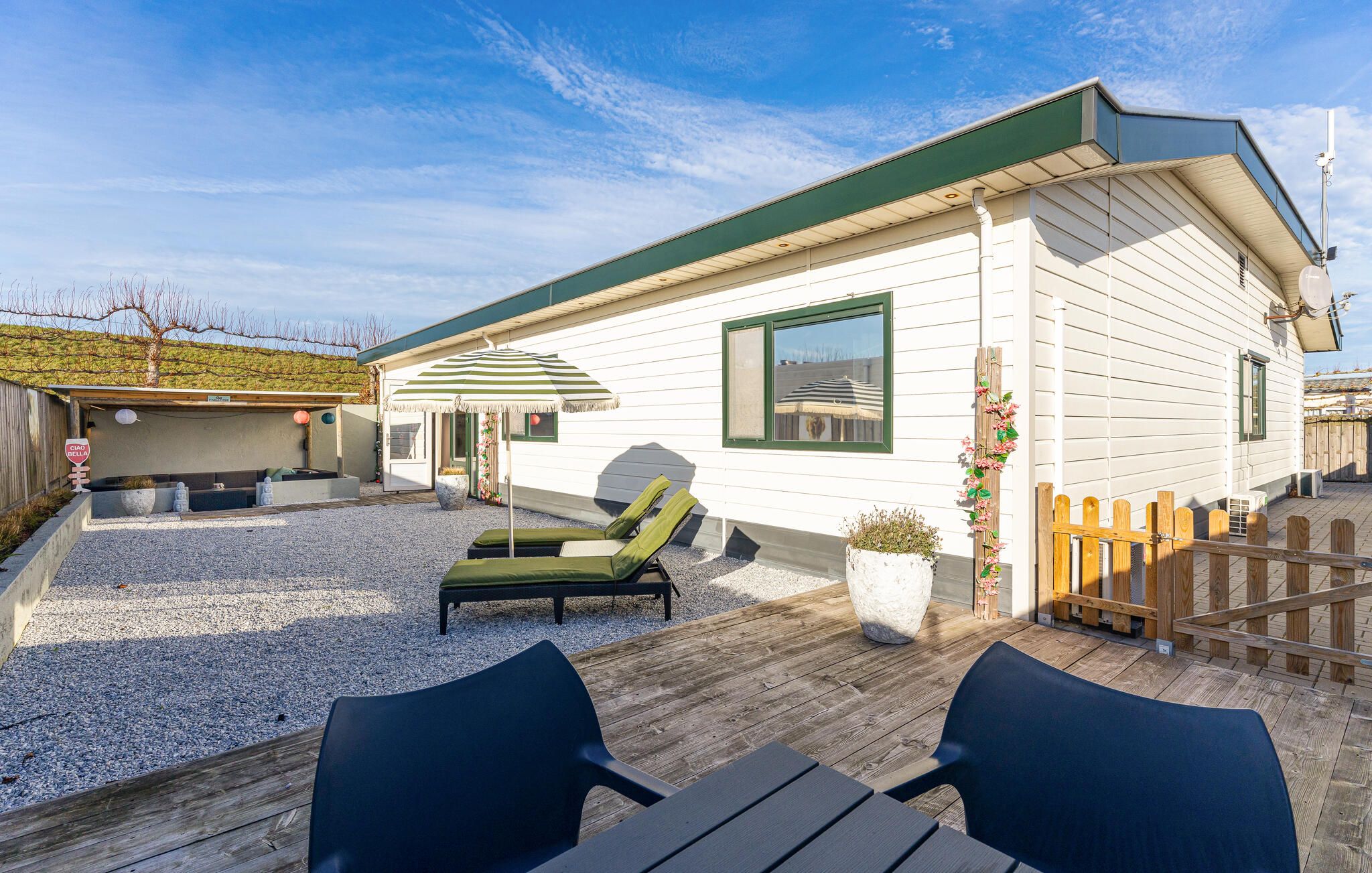 A mobile home with a covered patio area, outdoor seating, and a fenced yard.