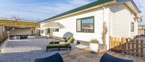 A mobile home with a covered patio area, outdoor seating, and a fenced yard.