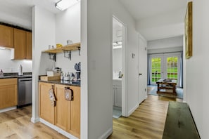 A modern kitchen with wooden cabinets, a countertop with various appliances, and a view into the adjacent dining area.