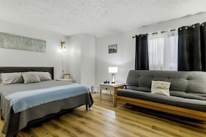 A bedroom with a bed, a sofa, a desk, and a nightstand.