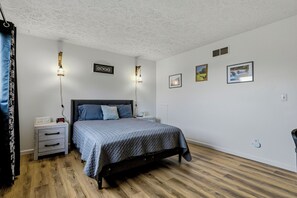 A bedroom with a bed, bedside tables, wall-mounted lights, and framed pictures.