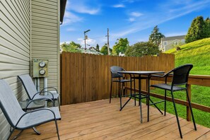 A deck with a table and chairs, a wooden fence, and a utility meter on the house.
