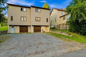 A two-story residential building with a gravel driveway and a fenced yard.