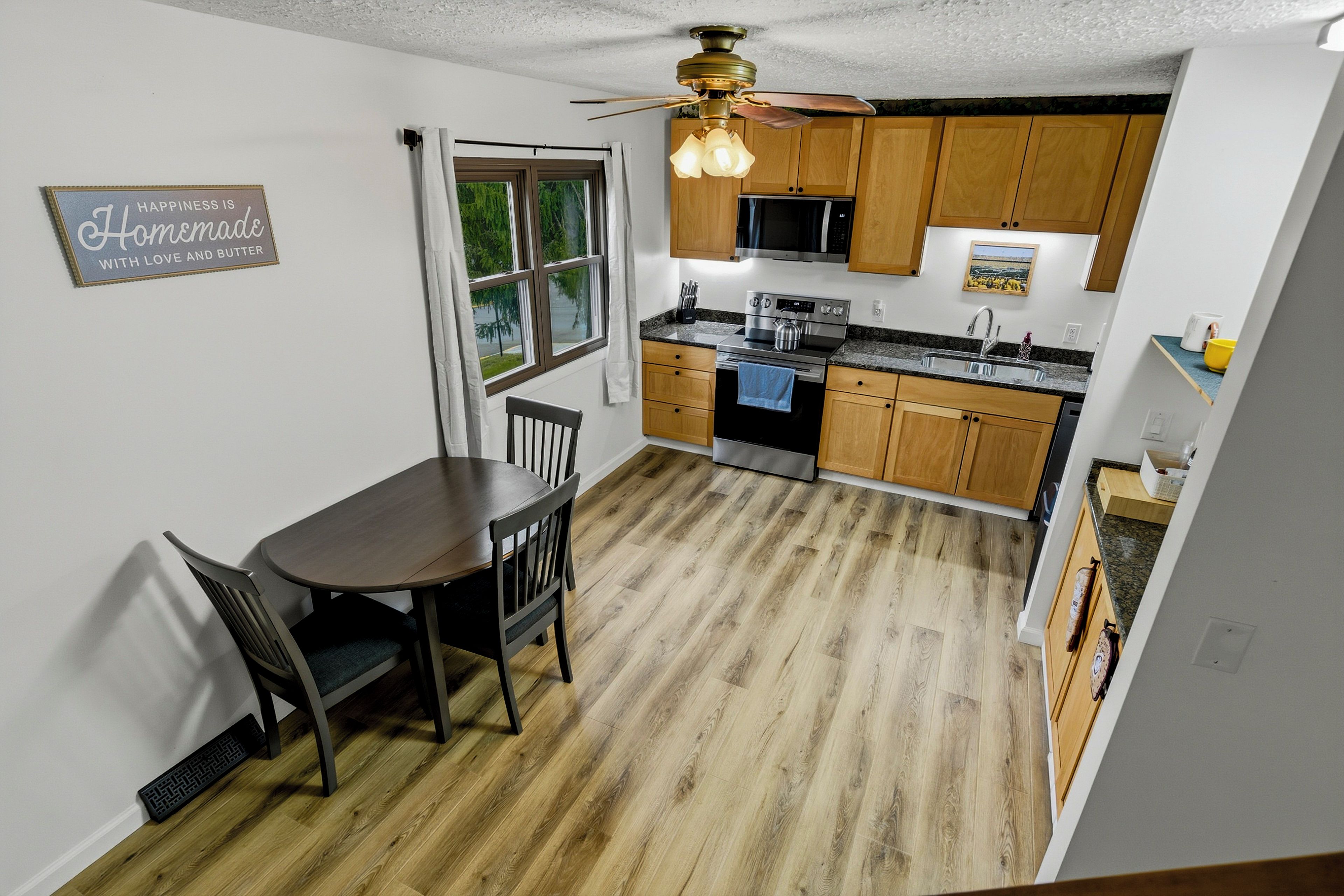 A modern kitchen with wooden cabinets, a dining table, and a ceiling fan.