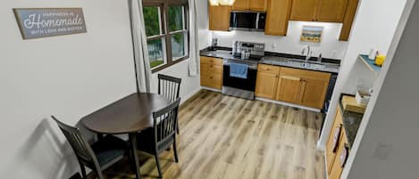 A modern kitchen with wooden cabinets, a dining table, and a ceiling fan.