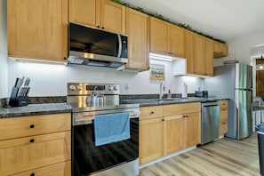 A modern kitchen with wooden cabinets, stainless steel appliances, and a granite countertop.