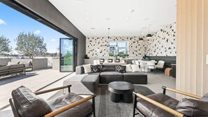 Zona d'estar moderna amb un sofà modular, una taula de centre rodona i butaques de pell.