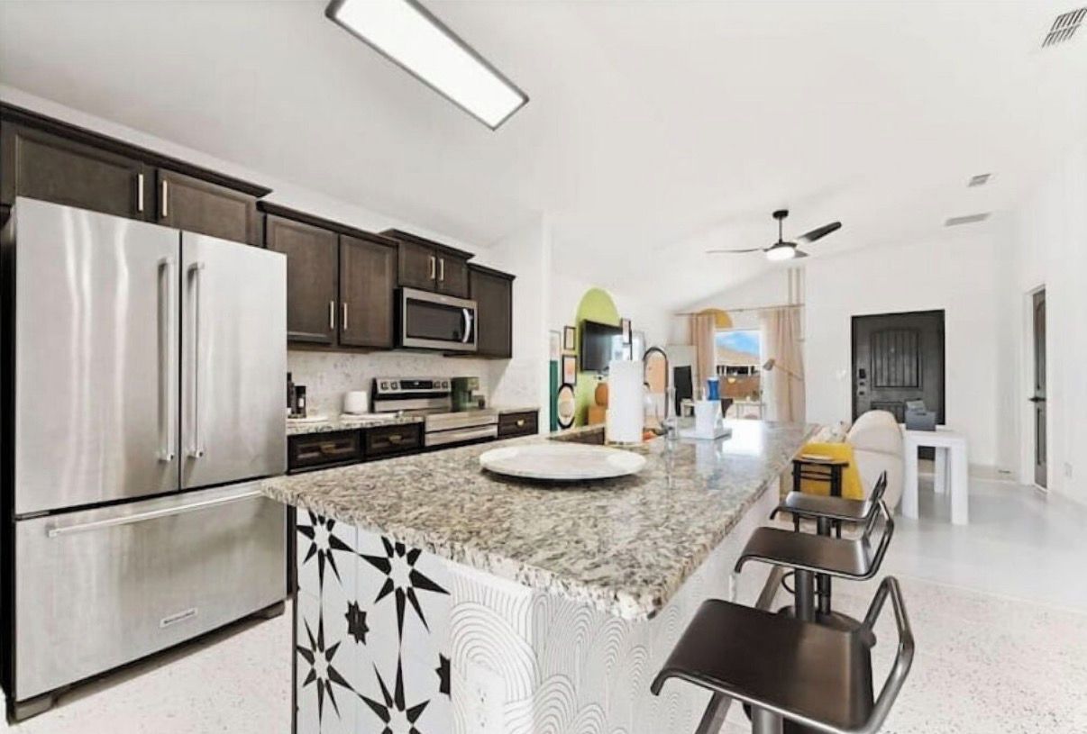 A modern kitchen with stainless steel appliances, a granite countertop, and a bar area.