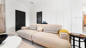 Ett modernt vardagsrum med en beige soffa, ett litet runt bord och en svart dörr.