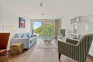 Ein modernes Wohnzimmer mit einer Couch, einem Sessel und einem Glastisch.