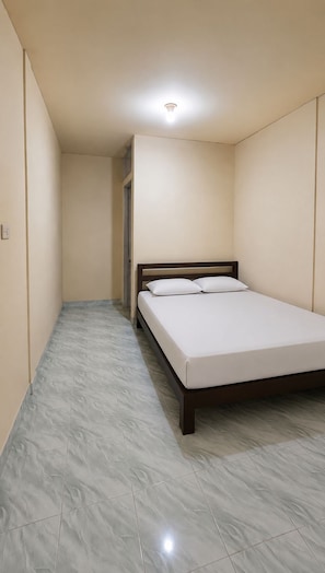 Un dormitorio con una cama individual, una puerta y una lámpara en el techo.