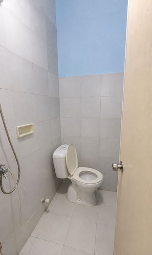 Un baño pequeño con azulejos, un inodoro, una ducha y una puerta.