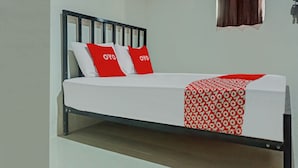 Ein Bett mit Metallgestell, weißer Bettwäsche und roten Kissen.