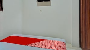 Ein Zimmer mit einem Bett, einem kleinen Fenster und einer Tür.