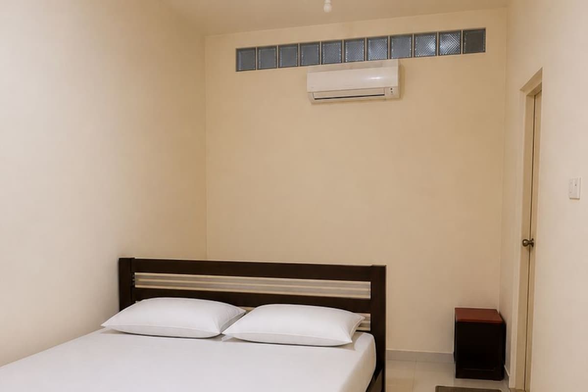 Un dormitorio con cama, aire acondicionado de pared y una puerta.