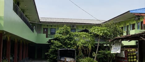 Un patio con una camioneta roja, una motocicleta y un edificio de fachada verde.