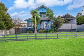 A two-story house with a blue exterior, a fenced front yard, and a clear sky. - Blue Vista Retreat - Apollo Bay (Apollo Bay)