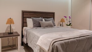 A neatly made bed with a wooden headboard, two bedside lamps, and a small table with a lamp. - Sonoran Star Beachfront 2BR - Ocean & Pool Views · Jacuzzi · Beach Access (Puerto Peñasco)