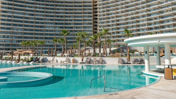 A hotel with a large pool area, multiple balconies, and palm trees. - Sonoran Star Beachfront 2BR - Ocean & Pool Views · Jacuzzi · Beach Access (Puerto Peñasco)