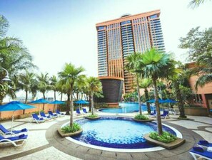 A hotel pool area with lounge chairs and palm trees. - Vacation Suite at Times Square KL (Kuala Lumpur)