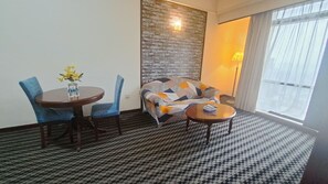 A hotel room with a dining table, two chairs, a sofa, and a small round table. - Vacation Suite at Times Square KL (Kuala Lumpur)