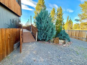 A gravel driveway leading to a wooden gate, surrounded by evergreen shrubs and a wooden fence. - River Front Getaway! Hot tub & Pool Table. Great location to Sunriver and Bend (Bend)