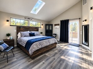 A bedroom with a large bed, a skylight, a wardrobe, and a view of the outdoors. - River Front Getaway! Hot tub & Pool Table. Great location to Sunriver and Bend (Bend)