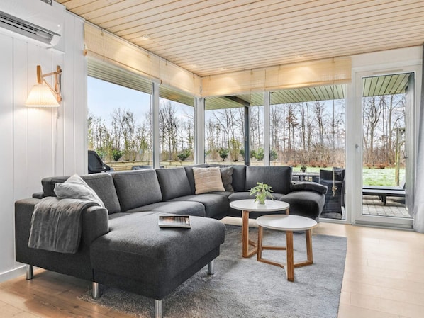 A modern living room with a sectional sofa, a small round table, and a large window offering a view of the outdoors.