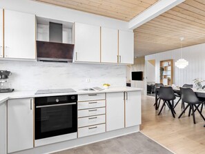A modern kitchen with white cabinetry, a built-in oven, and a marble countertop.