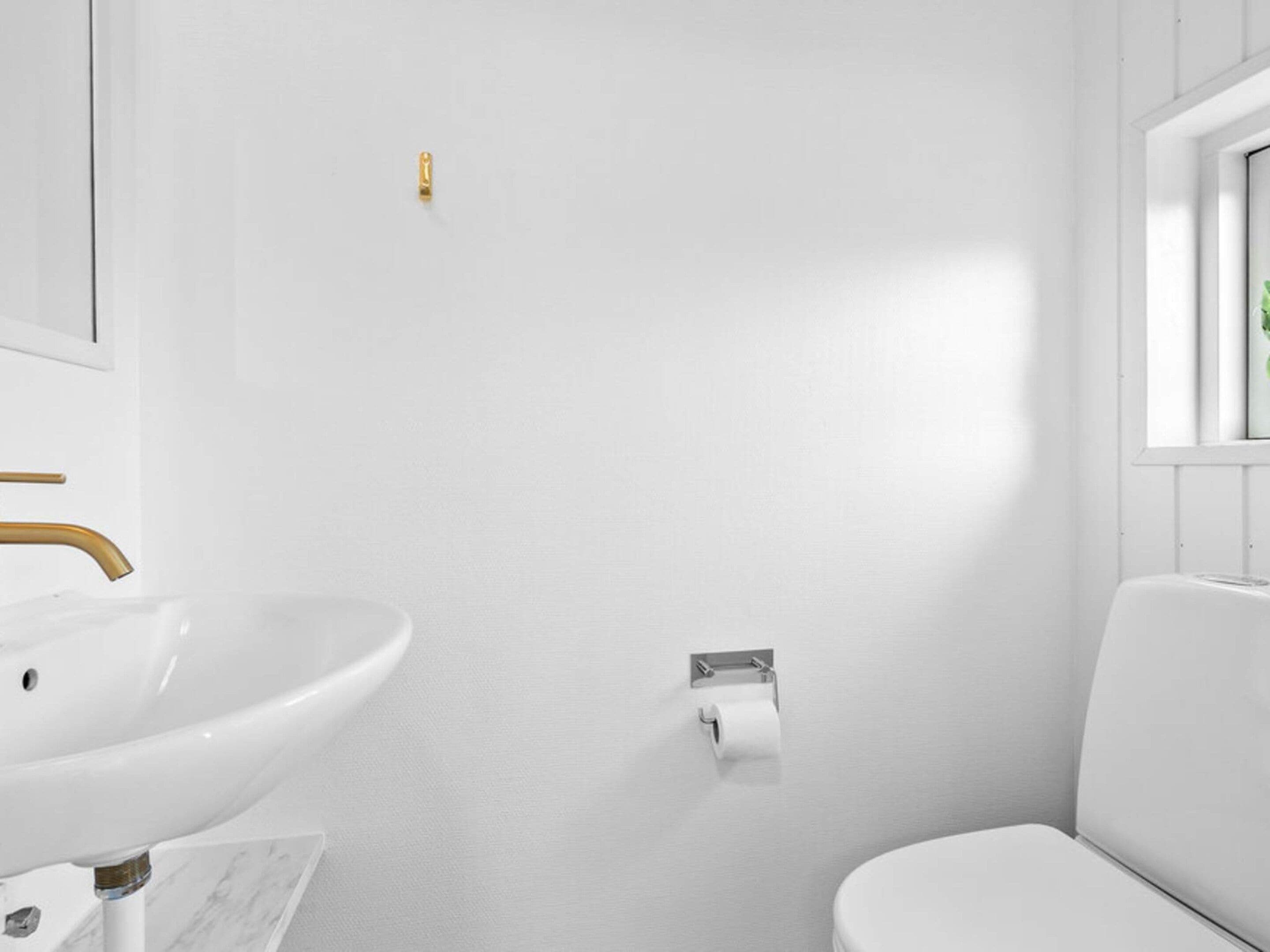 A bathroom with a white sink, toilet, and a mirror.