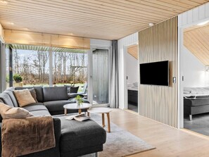 Ein modernes Wohnzimmer mit einer Eckcouch, einem Couchtisch und einem an der Wand befestigten Fernseher.
