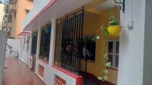 A residential building with barred windows, a red and white facade, and a hanging yellow basket. - Cosy family retreat on Nest & Nook Homestay in Kolkata (Kolkata)