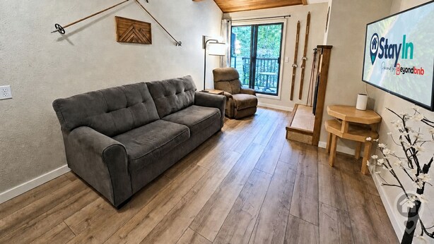 A living room with a gray sofa, a wooden coffee table, and a TV screen displaying 'StayIn'. - Ski-to-Door Condo, Kimberley Alpine Resort (Kimberley)