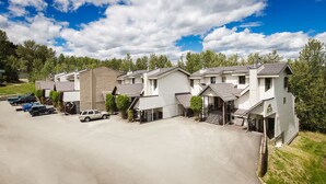 A row of single-story houses with attached garages, a paved driveway, and a parking area with several vehicles. - Ski-to-Door Condo, Kimberley Alpine Resort (Kimberley)
